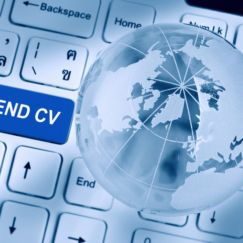 Send CV or curriculum vitae concept : Blue button on a white laptop computer keyboard inscribed or printed with words SEND CV, with a crystal clear globe and opaque world map. Vintage filter effect.